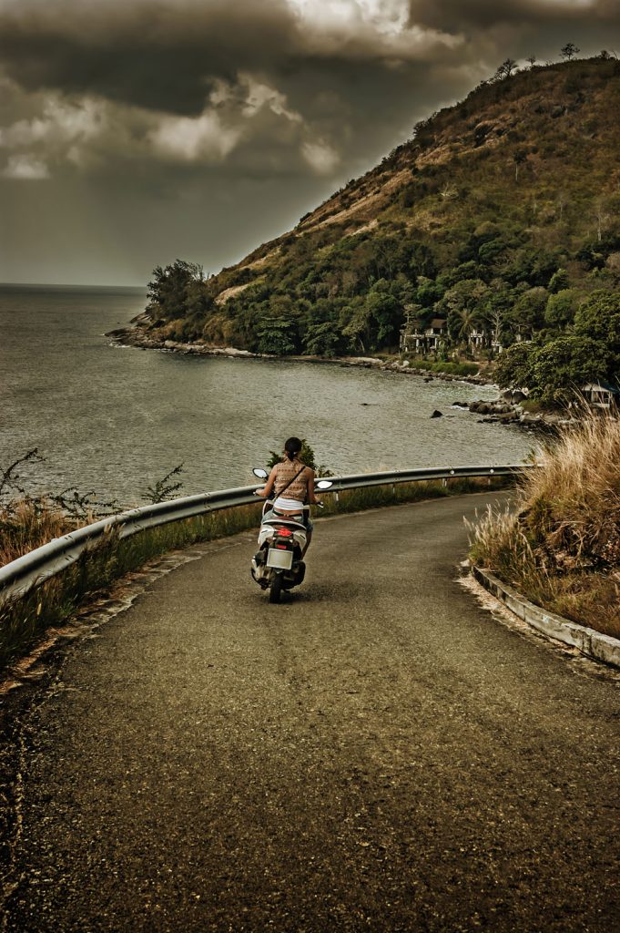 Девушка на мотоцикле едет по проселочной дороге, Таиланд